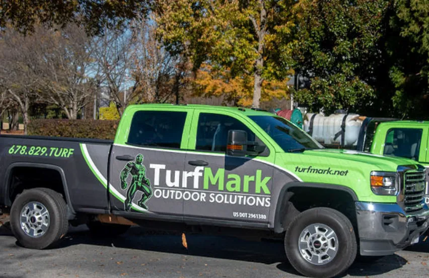 A green and gray TurfMark Outdoor Solutions truck